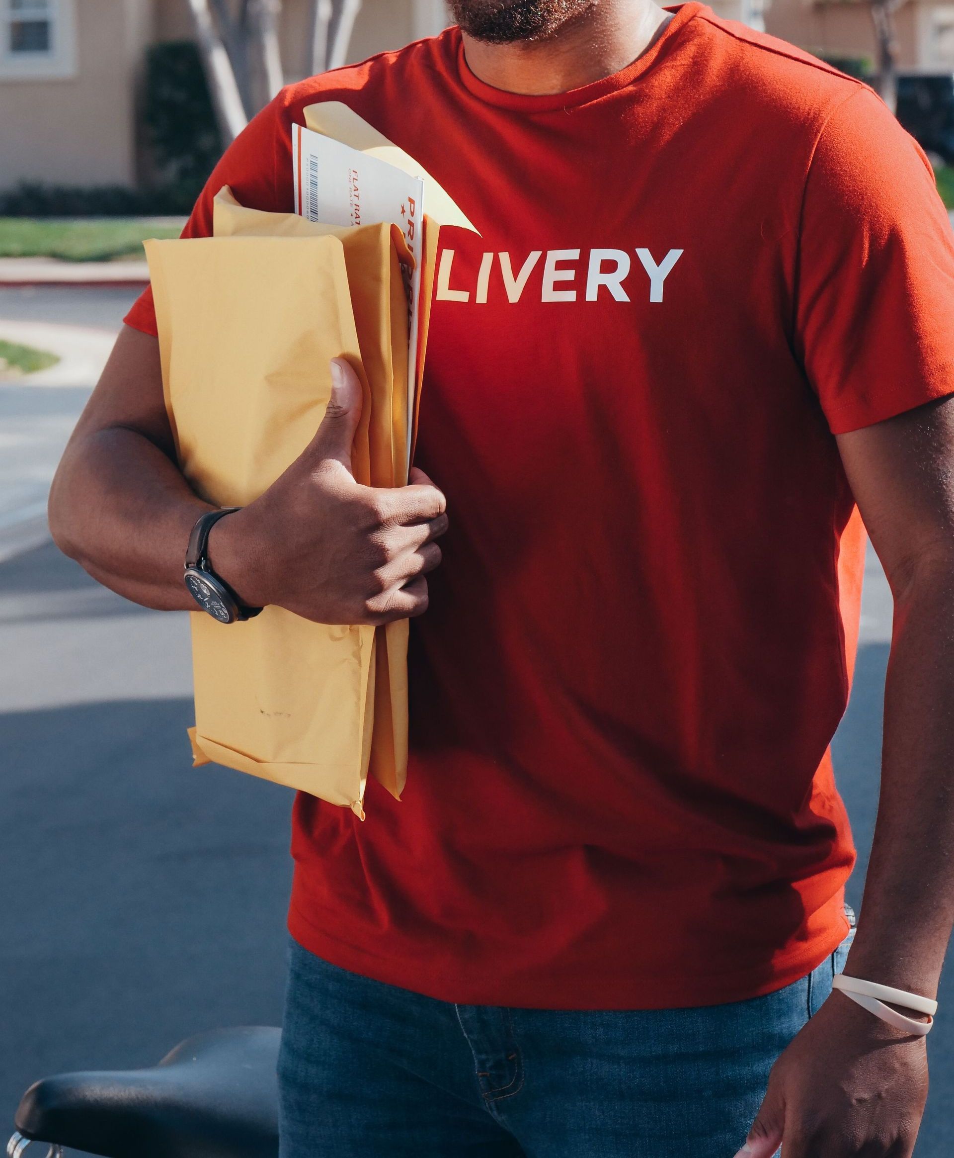 Cheerful delivery man holding packages in a sunny neighborhood setting.