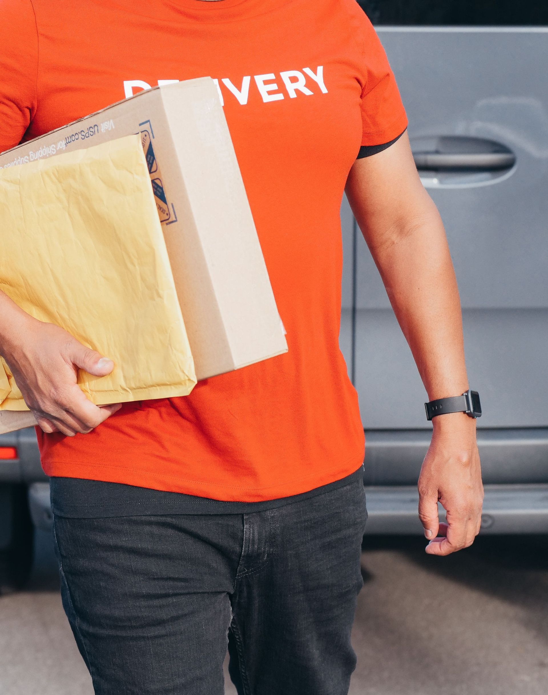 African American courier in a red shirt delivers packages with a smile outdoors. Perfect for delivery service concepts.